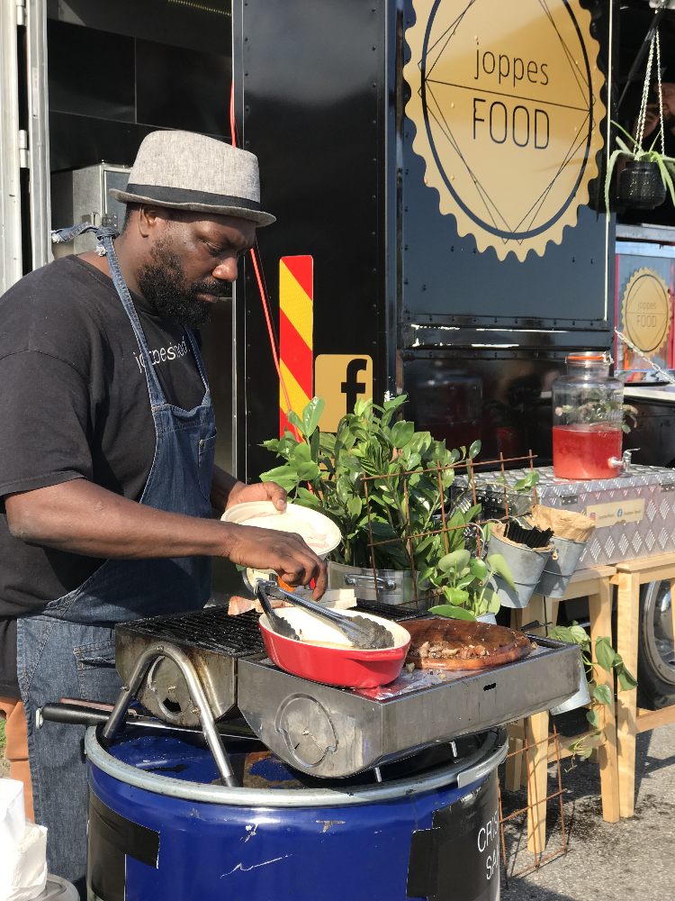 Joppe lägger upp mat vid grillen framför sin food truck